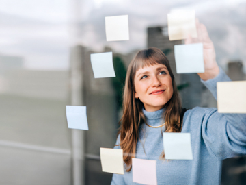 Eine Frau steht am Fenster an dem Post-Its befestigt sind